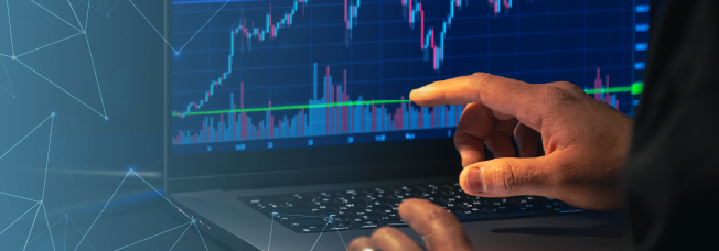 Profissional do mercado financeiro mostrando gráficos no computador.